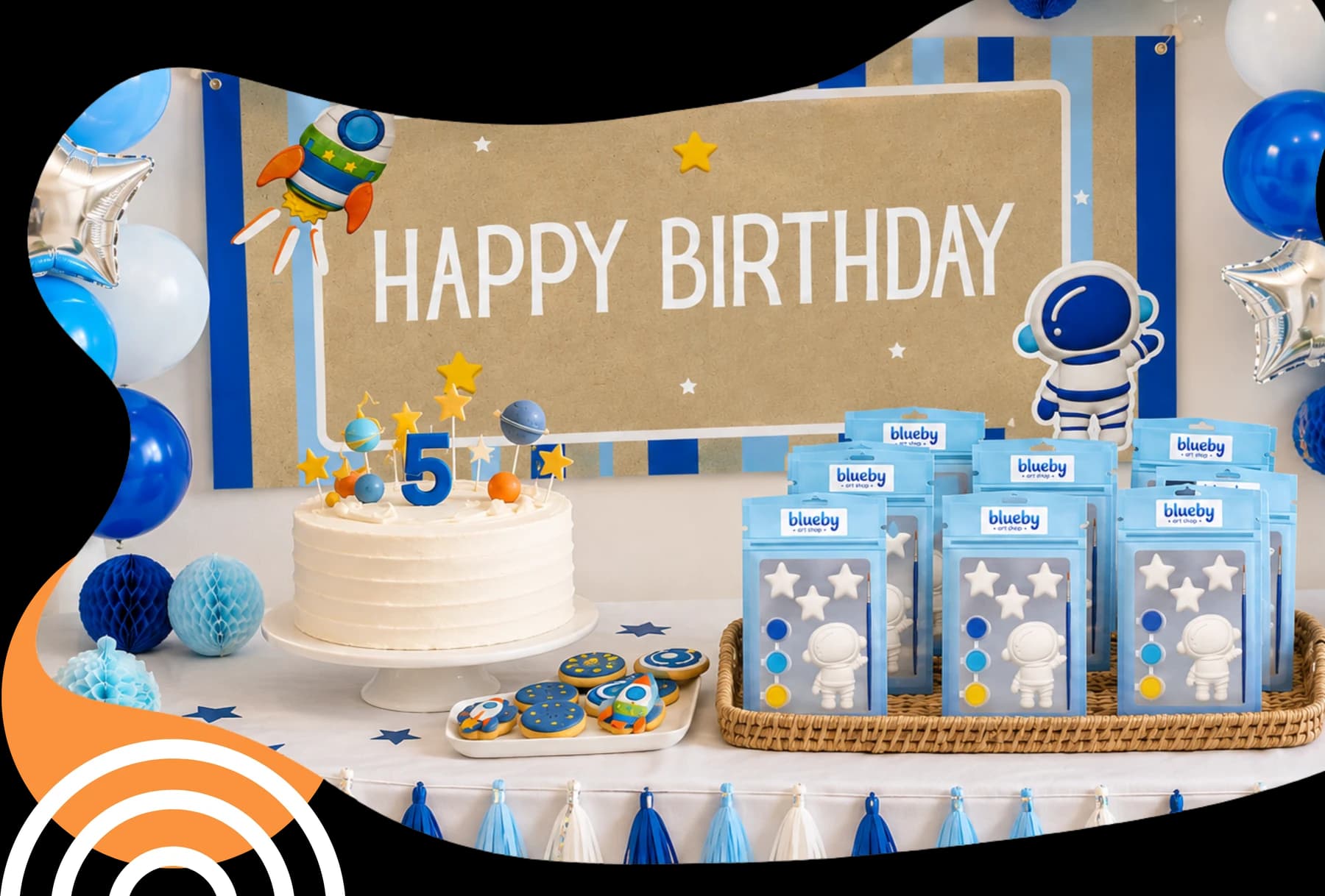 A space-themed birthday table with a Happy Birthday banner, cake, balloons and a basket of Blueby party favour kits