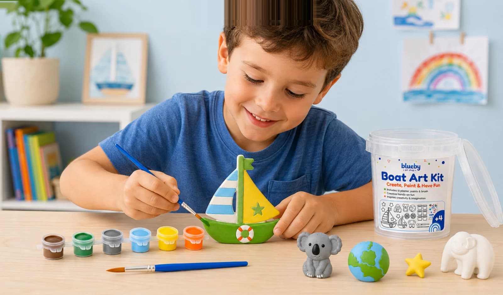 A boy painting the plaster sailboat from his Blueby Boat Art Kit at a table